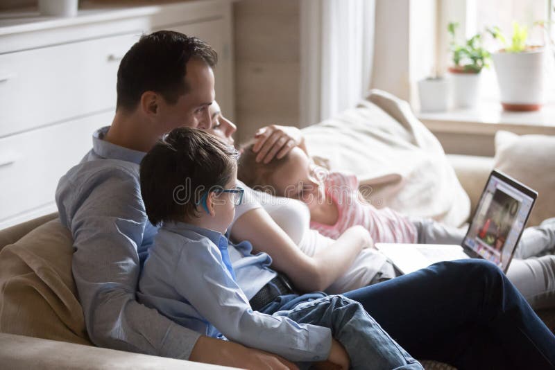 Gl? ckliches Familienausgabenwochenende zu Hause Film auf Computer aufpassend lizenzfreies stockfoto