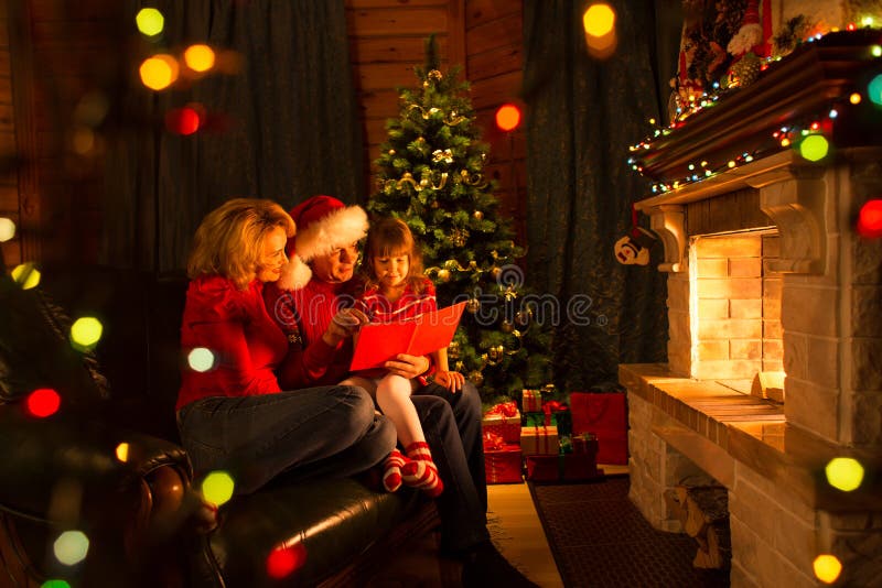 Glückliches Familienlese-Buch zu Hause durch Kamin im warmen und gemütlichen Wohnzimmer auf Wintertag-christmastime stockfoto Glückliches Familienlese-Buch zu Hause durch Kamin im warmen und gemütlichen Wohnzimmer auf Wintertag-christmastime stockfoto