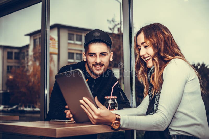 Glückliches junges Paar benutzt eine Tablette lizenzfreies stockfoto Glückliches junges Paar benutzt eine Tablette lizenzfreies stockfoto
