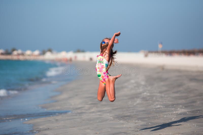 Glückliches Kind, das in Sommerferien auf exotischem tropischem Strand springt lizenzfreie stockfotos Glückliches Kind, das in Sommerferien auf exotischem tropischem Strand springt lizenzfreie stockfotos