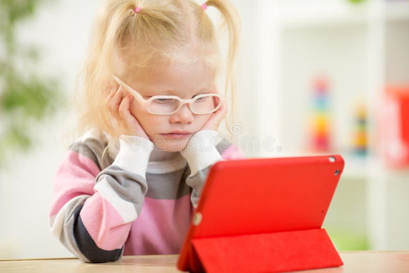 Glückliches Kind in den Gläsern, die Minitabletten-PC betrachten stockfotografie Glückliches Kind in den Gläsern, die Minitabletten-PC betrachten stockfotografie