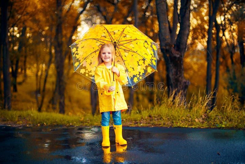 Glückliches Kindermädchen mit einem Regenschirm und Gummistiefel ein Herbst gehen stockfotos Glückliches Kindermädchen mit einem Regenschirm und Gummistiefel ein Herbst gehen stockfotos