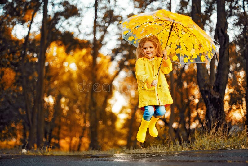 Glückliches Kindermädchen mit einem Regenschirm und Gummistiefel ein Herbst gehen lizenzfreie stockfotografie Glückliches Kindermädchen mit einem Regenschirm und Gummistiefel ein Herbst gehen lizenzfreie stockfotografie