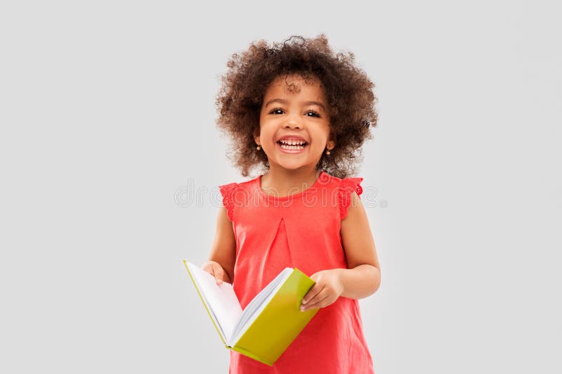 Glückliches kleines Afroamerikanermädchen mit Buch lizenzfreie stockbilder Glückliches kleines Afroamerikanermädchen mit Buch lizenzfreie stockbilder
