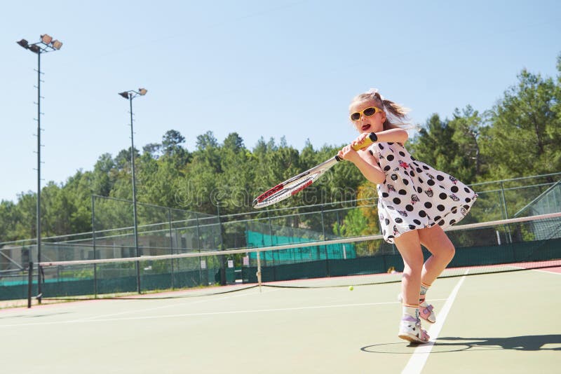 Glückliches kleines Mädchen, das Tennis spielt stockfotografie Glückliches kleines Mädchen, das Tennis spielt stockfotografie