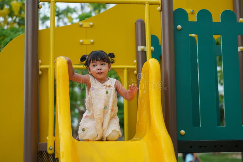 Glückliches Kleinkind, das auf dem Spielplatz im Park spielt stockfotos