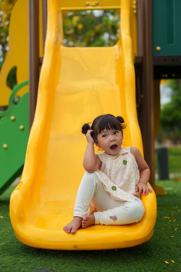 Glückliches Kleinkind, das auf dem Spielplatz rutscht und spielt lizenzfreie stockfotos