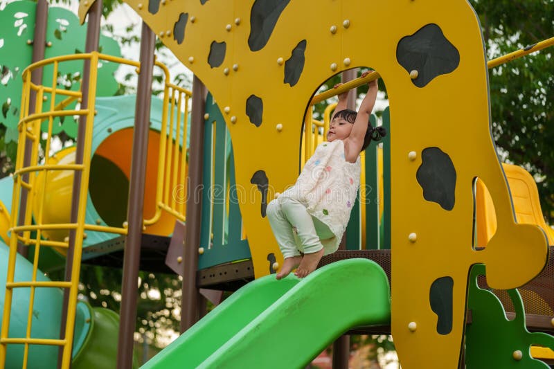 Glückliches Kleinkind, das die gelbe Bar an der Hand am Spielplatz im Park im Freien hängt lizenzfreies stockbild