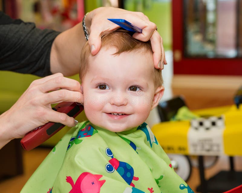 Glückliches Kleinkind, das seinen ersten Haarschnitt erhält stockfotografie Glückliches Kleinkind, das seinen ersten Haarschnitt erhält stockfotografie