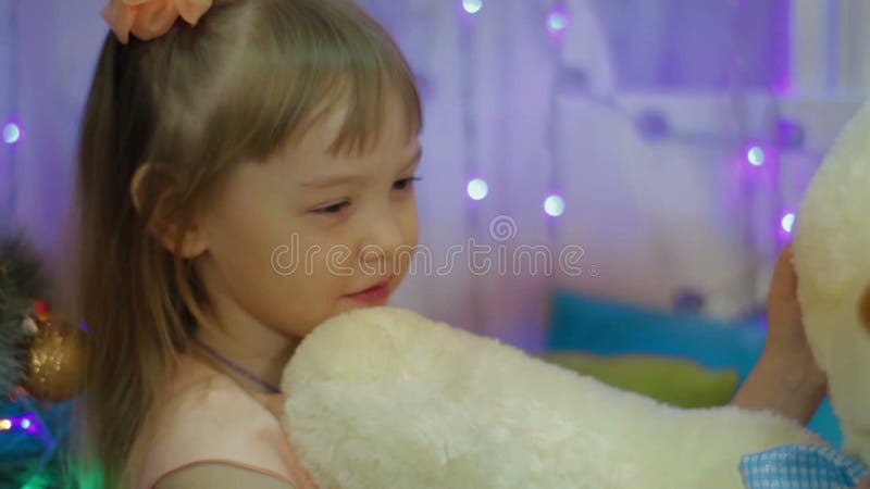 Glückliches Mädchen, das einen Teddybären umarmt Geschenk für neues Jahr für Kind