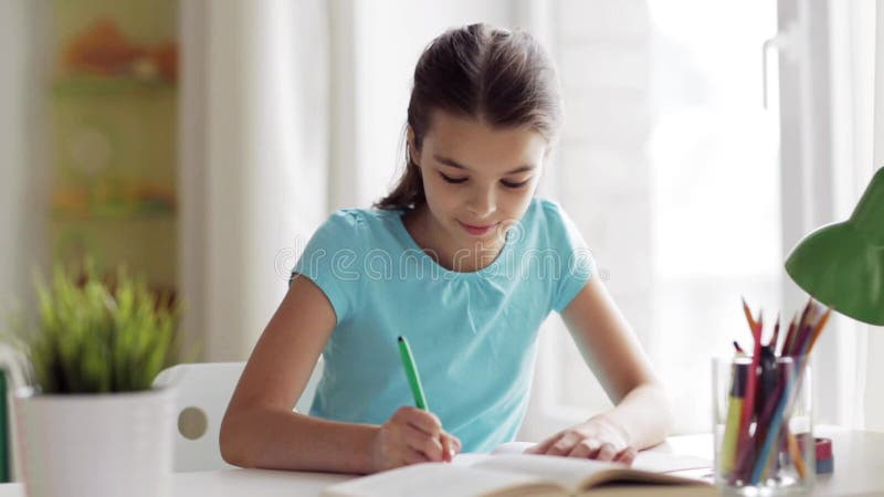 Glückliches Mädchen mit Buch zu Hause schreibend zum Notizbuch