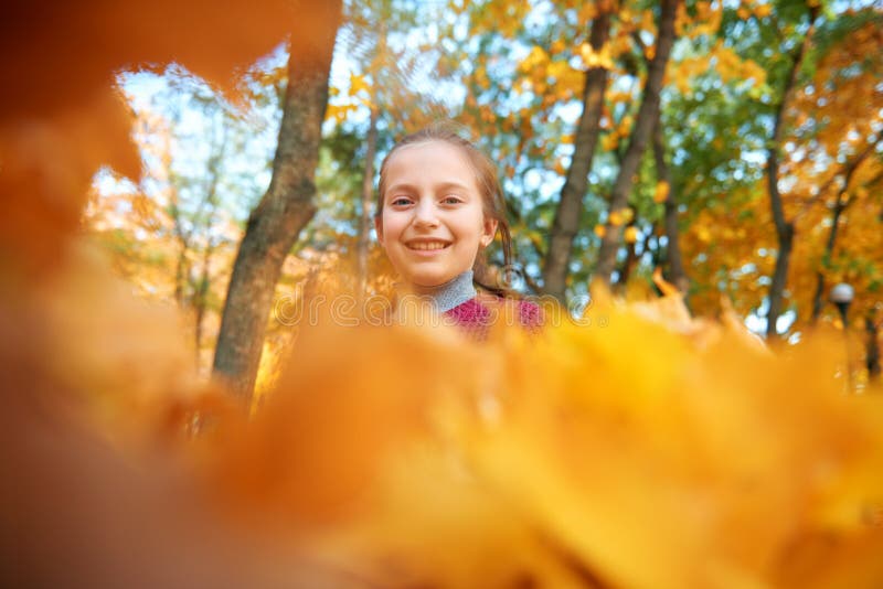 Glückliches Mädchen spielt und schaut durch gelbe Blätter im Herbststädtpark Hellgelbe Bäume und Blätter lizenzfreies stockfoto Glückliches Mädchen spielt und schaut durch gelbe Blätter im Herbststädtpark Hellgelbe Bäume und Blätter lizenzfreies stockfoto