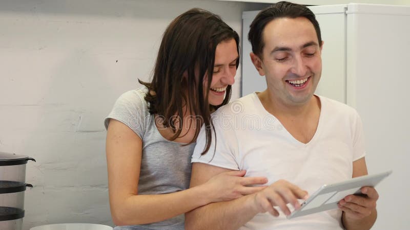 Glückliches Paar benutzt Tablet beim Sitzen am Küchentisch