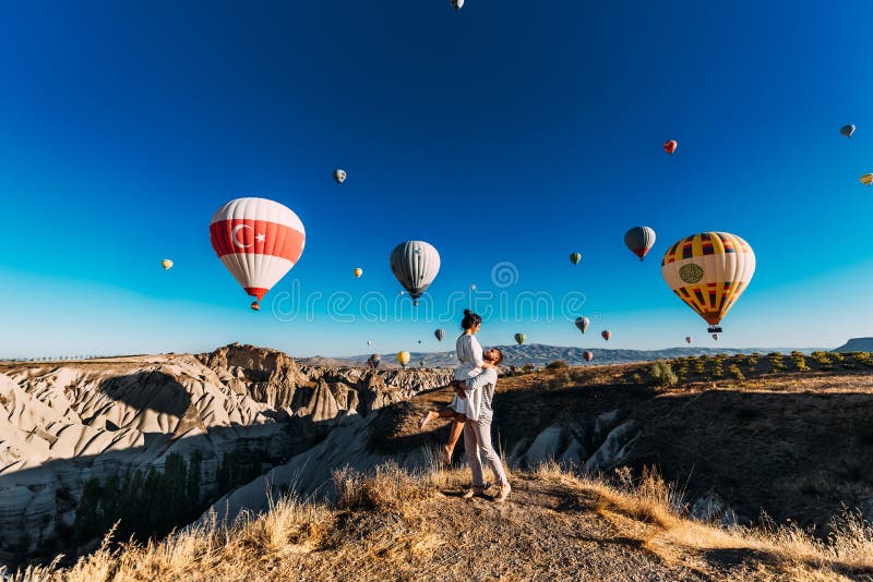 Glückliches Paar in Cappadocia Der Mann schlug zum Mädchen vor Flitterwochen in Cappadocia Verbinden Sie am Ballonfestival Flitte stockfoto Glückliches Paar in Cappadocia Der Mann schlug zum Mädchen vor Flitterwochen in Cappadocia Verbinden Sie am Ballonfestival Flitte stockfoto