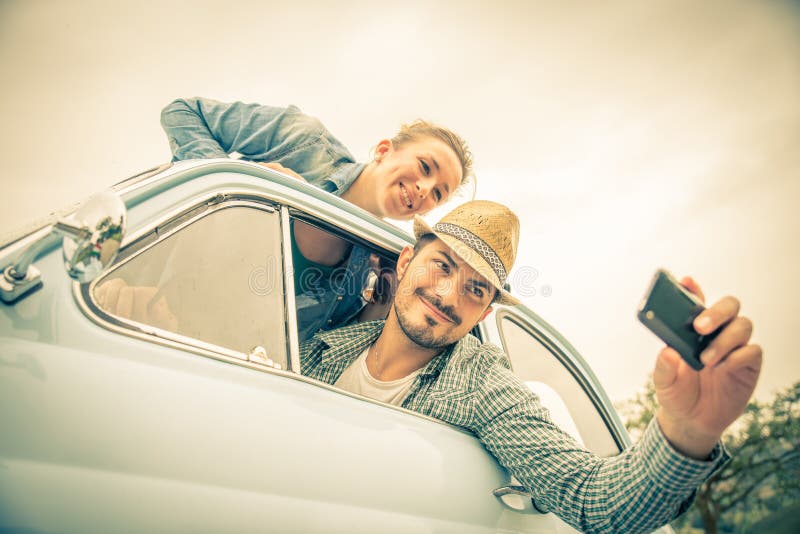 Happy couple on vintage car - Two friends photographing on a road trip - Concepts of couple, travel and fun. Happy couple on vintage car - Two friends photographing on a road trip - Concepts of couple, travel and fun