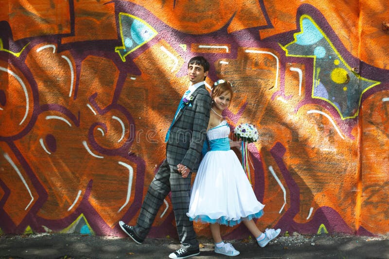 Glückliches Paar, das auf Hintergrundgraffiti aufwirft stockfotografie Glückliches Paar, das auf Hintergrundgraffiti aufwirft stockfotografie