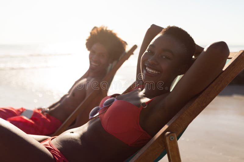 Glückliches Paar, das in einem Strandstuhl auf dem Strand sich entspannt lizenzfreie stockfotografie Glückliches Paar, das in einem Strandstuhl auf dem Strand sich entspannt lizenzfreie stockfotografie