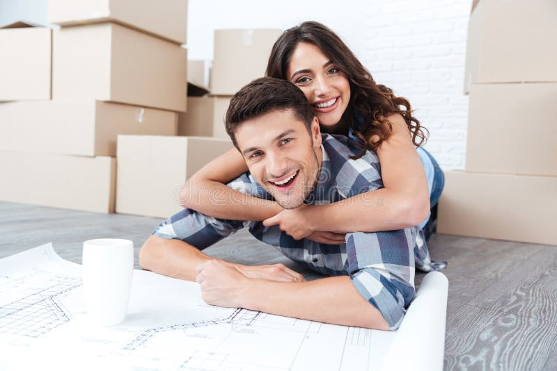 Glückliches Paar, das Pläne des neuen Hauses betrachtet lizenzfreies stockfoto Glückliches Paar, das Pläne des neuen Hauses betrachtet lizenzfreies stockfoto