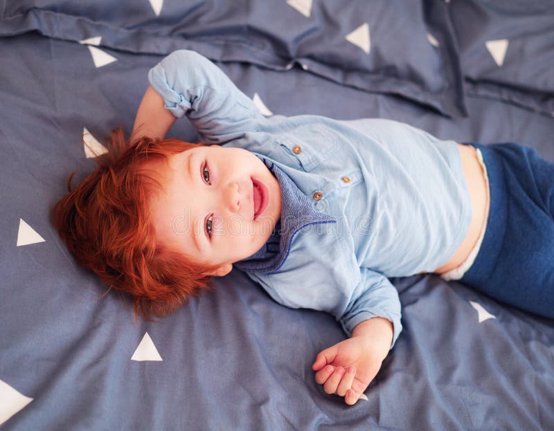Glückliches Rothaarigekleinkindbaby, das Spaß im Bett hat lizenzfreie stockfotos