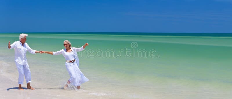 Glückliches älteres Paar-Tanzen, das Hände auf einem tropischen Strand anhält