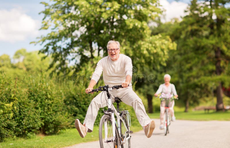 Active old age, people and lifestyle concept - happy senior couple riding bicycles at summer park. Active old age, people and lifestyle concept - happy senior couple riding bicycles at summer park