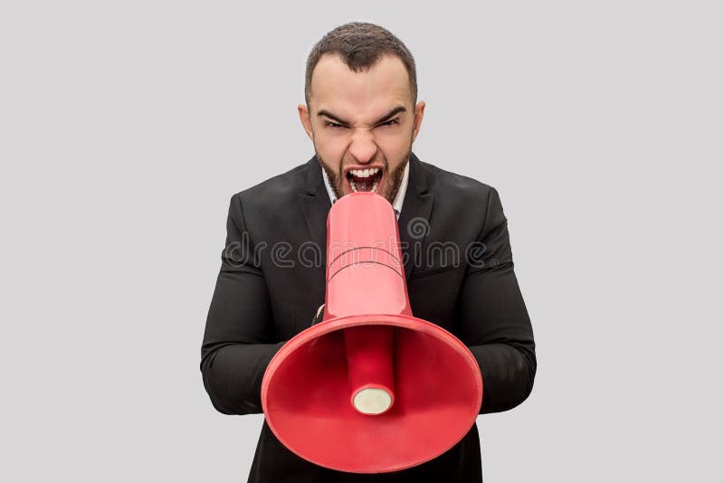 Gniewny młody człowiek krzyczy w czerwonego megafon Trzyma mnie z oba rękami Młody człowiek jest szalenie Odizolowywający na biel obrazy royalty free Gniewny młody człowiek krzyczy w czerwonego megafon Trzyma mnie z oba rękami Młody człowiek jest szalenie Odizolowywający na biel obrazy royalty free