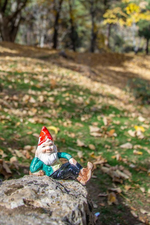 Gnome lying on a rock with the autumn ocher forest in the background. Vertical image. In Granada