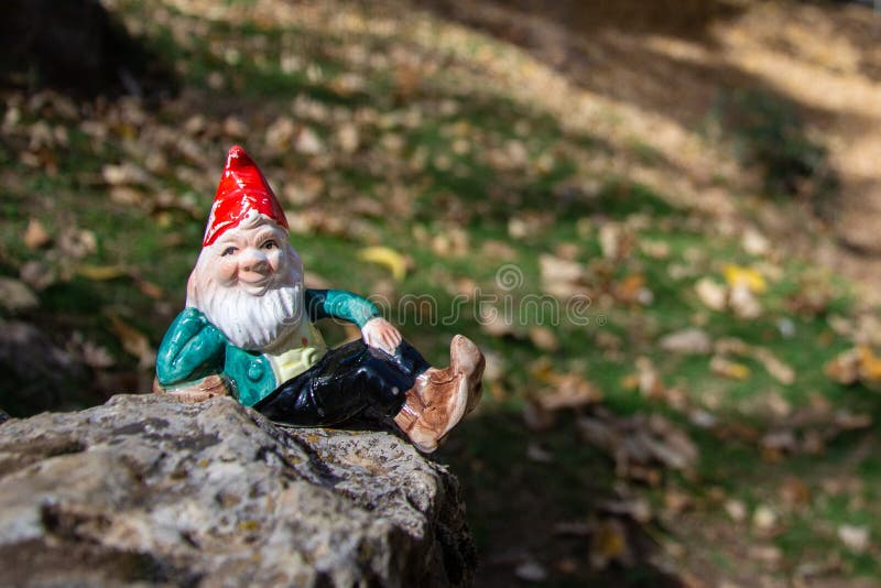 Gnome lying on a rock surrounded by autumn ocher leaves. Horizontal picture. In Granada