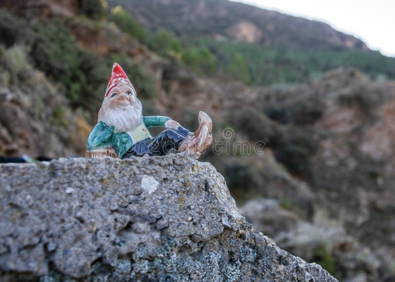 Gnome lying on a stone and mountains in the background with vegetation in Alpujarra