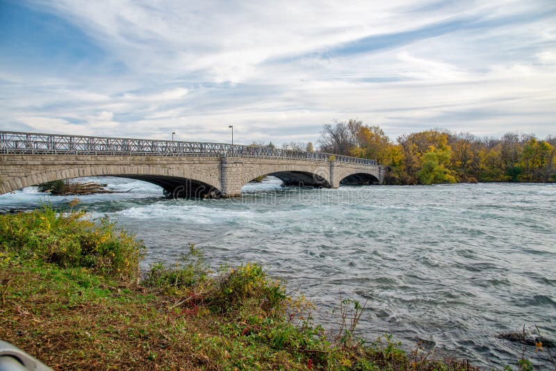 Goat Island Bridge in Niagara Falls State Park, upstream of Niagara Falls waterfall with beautiful autumn leaves foliage sunset