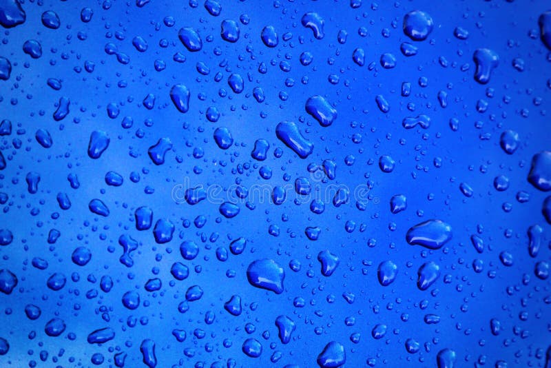 Gocce di pioggia sulla carrozzeria blu, fuoco basso fotografia stock Gocce di pioggia sulla carrozzeria blu, fuoco basso fotografia stock