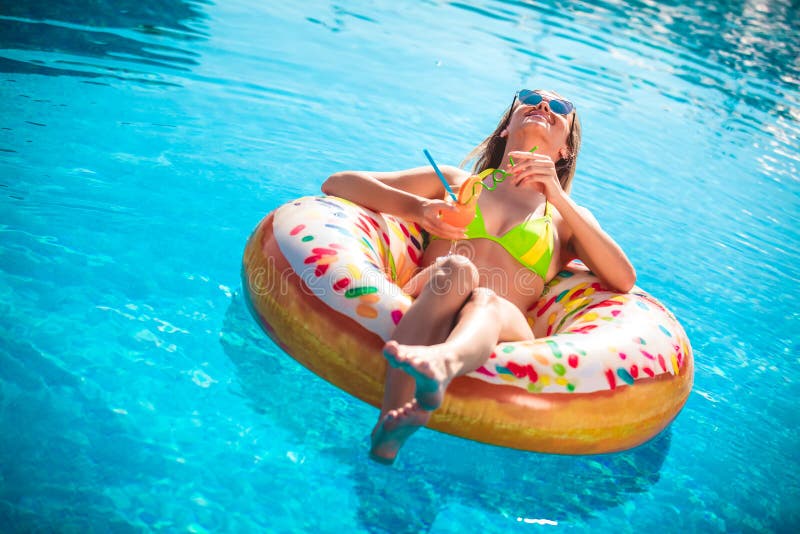 Godere della donna di abbronzatura in bikini sul materasso gonfiabile nella piscina immagine stock Godere della donna di abbronzatura in bikini sul materasso gonfiabile nella piscina immagine stock