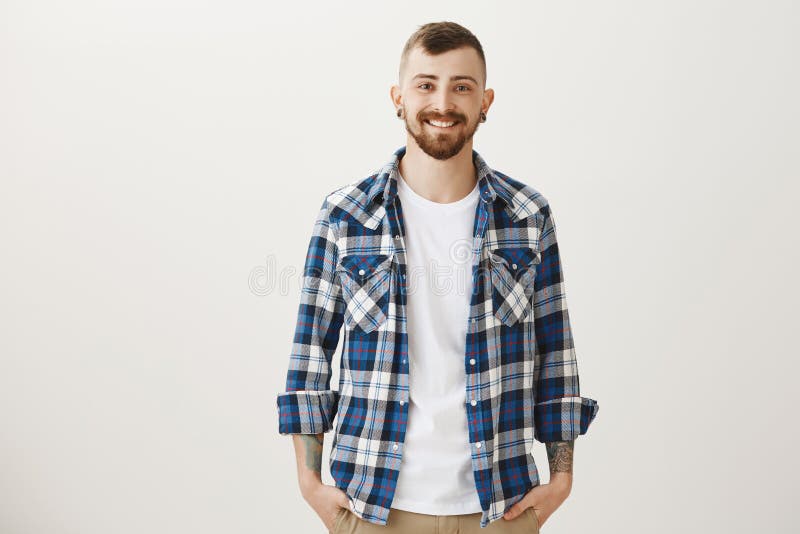 Goed-Looing zekere volwassen vriend met vlees-tunnels en baard die zich in blauw plaidoverhemd bevinden over grijze achtergrond royalty-vrije stock foto Goed-Looing zekere volwassen vriend met vlees-tunnels en baard die zich in blauw plaidoverhemd bevinden over grijze achtergrond royalty-vrije stock foto