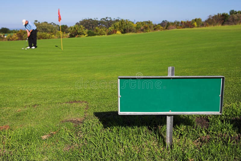 A golfer playing golf on a green. Shallow D.O.F - sign in focus, golfer out of focus. A golfer playing golf on a green. Shallow D.O.F - sign in focus, golfer out of focus.