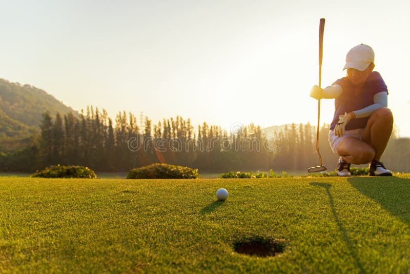 Gofer Aziatische vrouwen die golfbal zetten stock afbeeldingen Gofer Aziatische vrouwen die golfbal zetten stock afbeeldingen