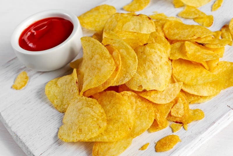 Gold and Crispy Potato Chips with Hot Sauce on White Board, Background
