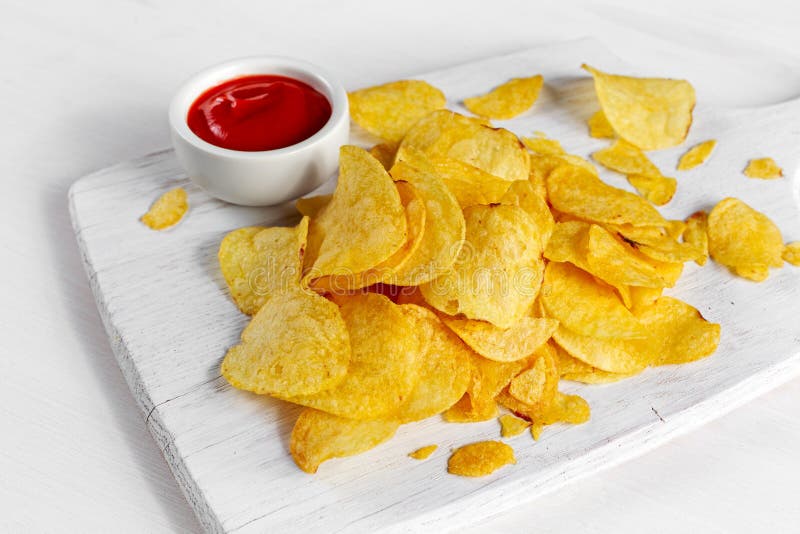 Gold and Crispy Potato Chips with Hot Sauce on White Board, Background