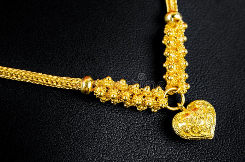 Gold Necklace and Heart Shape Pendant on Black Leather Stock Image