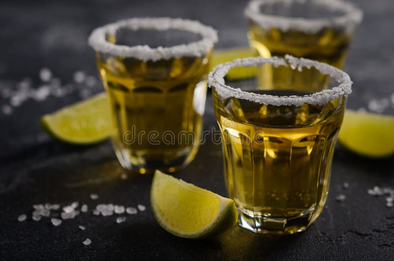 Gold Tequila with Lime and Salt Rim on Dark Stone or Concrete