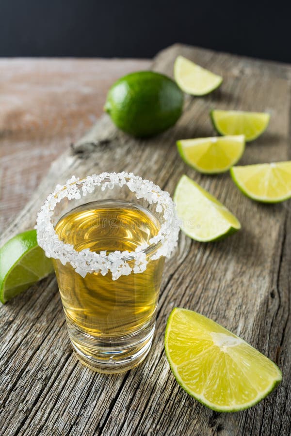 Gold tequila shot with lime slices on rustic wooden table royalty free stock photography Gold tequila shot with lime slices on rustic wooden table royalty free stock photography