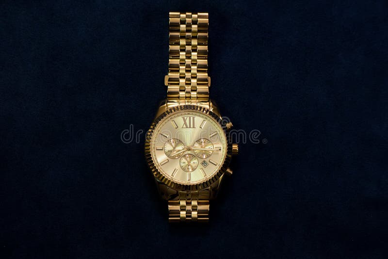 Gold wristwatch with a yellow metal bracelet on a dark blue back