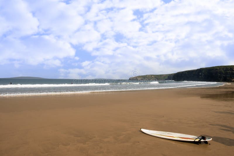 Golden beach with lone surfboard