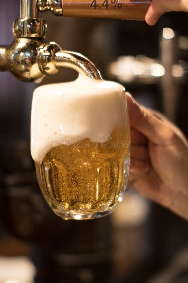 Golden Beer Tap with Beer Mug on Bar Stand and Hand Pulling a Natural
