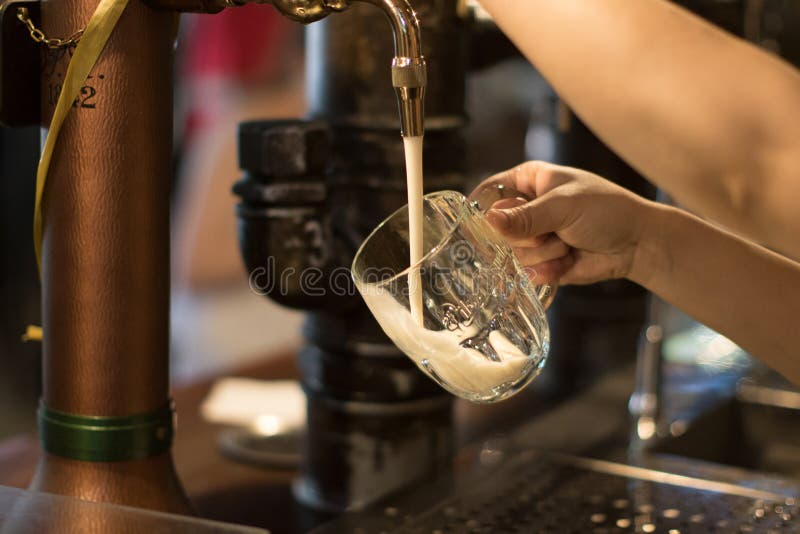Golden Beer Tap with Beer Mug on Bar Stand and Hand Pulling a Natural