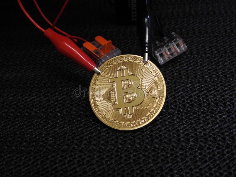 Golden Bitcoin with alligator clips stock image