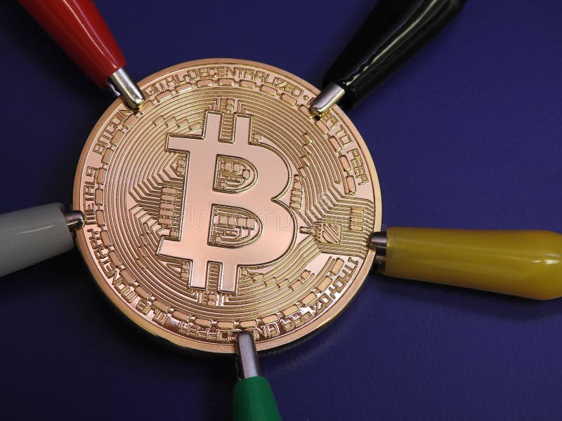 Golden Bitcoin with alligator clips royalty free stock image