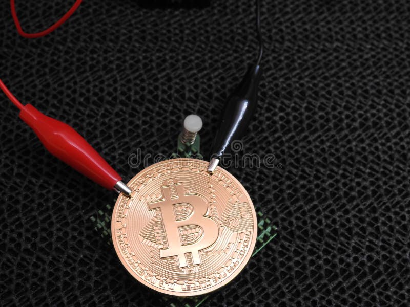 Golden Bitcoin with alligator clips royalty free stock photos