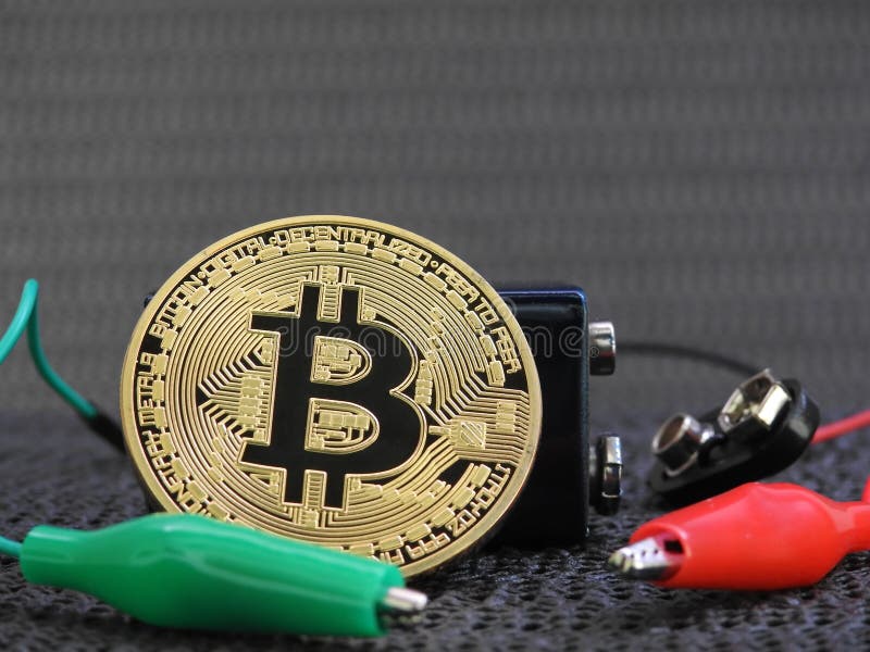 Golden Bitcoin with battery and alligator clips stock photography