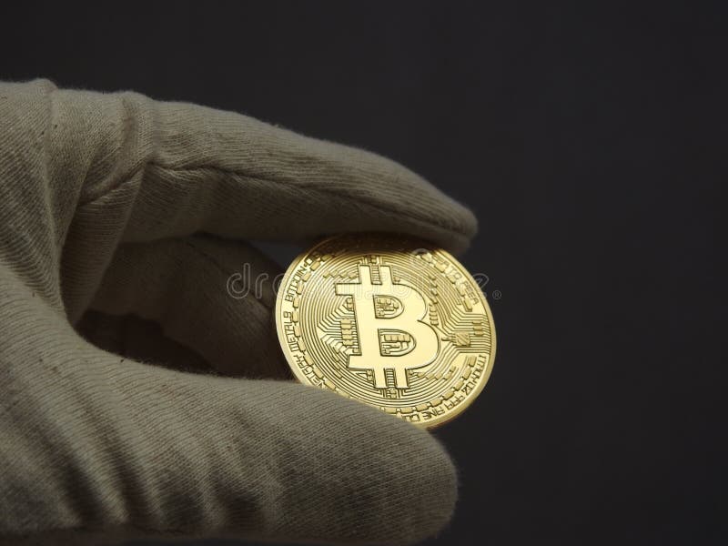 Golden Bitcoin handled with gloves. royalty free stock photography
