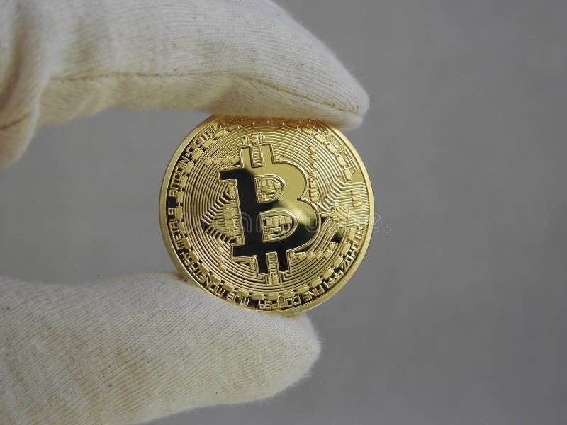 Golden Bitcoin handled with gloves. royalty free stock images